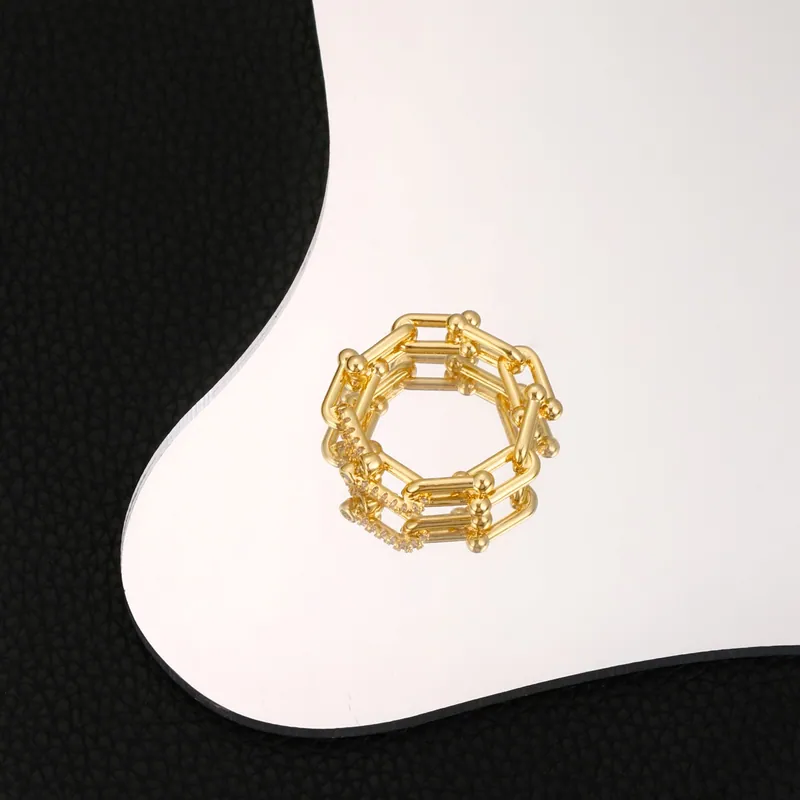 Angular link ring; gold tone, sculptural design. Full-frame photograph with existing branding.