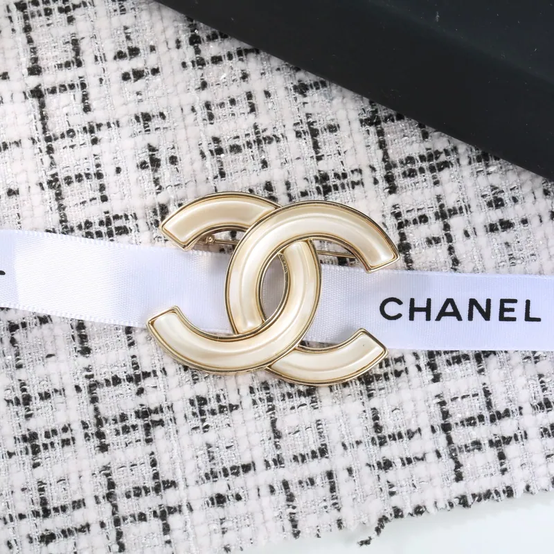 Tweed-backdrop emblem brooch; gold tone, statement design. Full-frame photograph with existing branding.