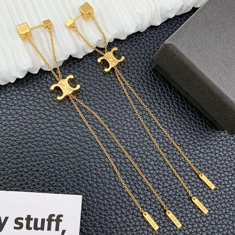 Emblem chain-drop earrings; gold tone, statement design. Full-frame photograph with existing branding.